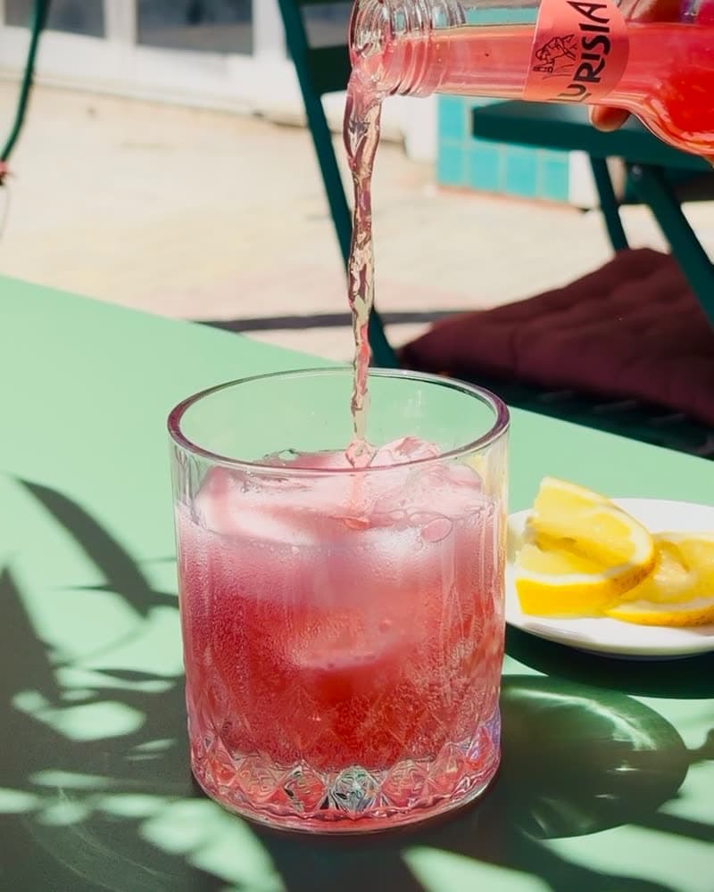 Pink spritz poured over ice on a green table
